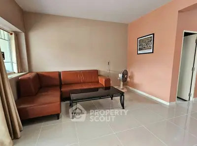 Spacious living room with modern leather sofa and sleek tiled flooring.