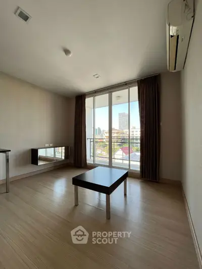 Spacious living room with large windows and city view, featuring modern minimalist decor.