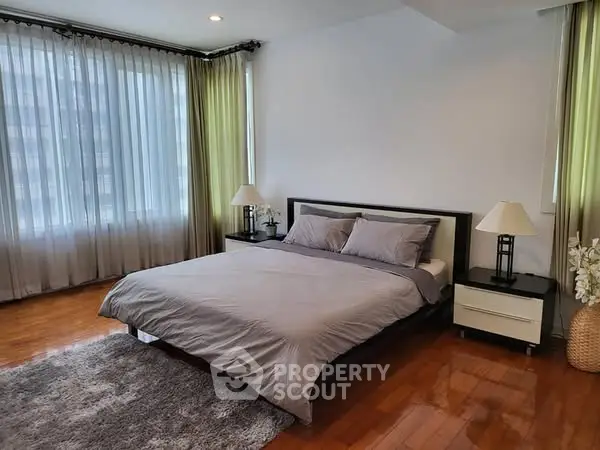 Spacious bedroom with modern decor and large windows for natural light.