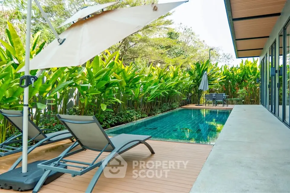 Luxurious private pool area with lush greenery and modern sun loungers, perfect for relaxation.