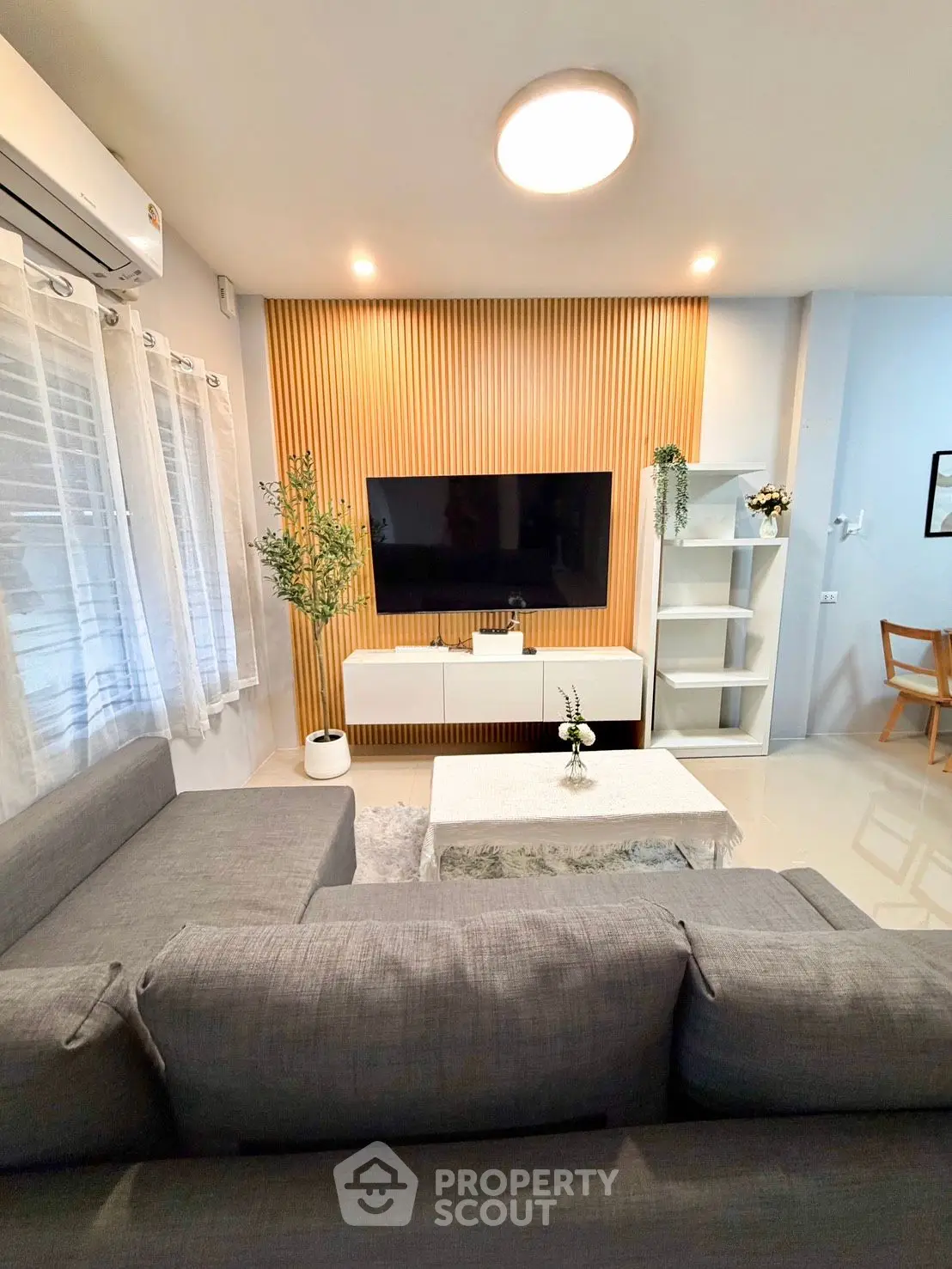 Modern living room with stylish decor, featuring a cozy gray sofa, sleek TV unit, and elegant lighting.