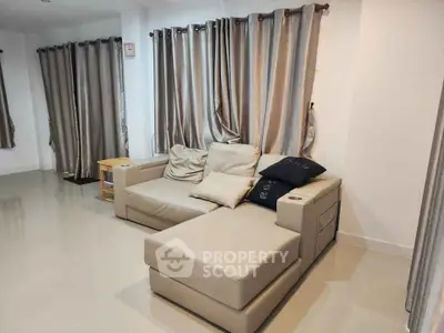 Spacious living room with modern beige sofa and elegant curtains, perfect for relaxation and entertainment.