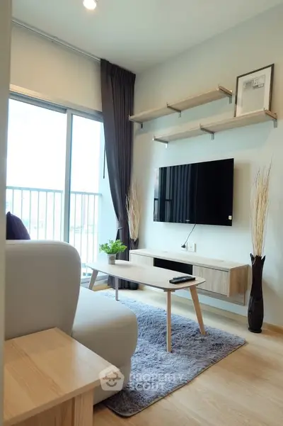Modern living room with sleek furniture and wall-mounted TV, featuring a cozy rug and natural light from large windows.