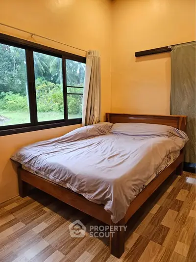 Cozy bedroom with wooden bed frame and scenic window view, perfect for relaxation.