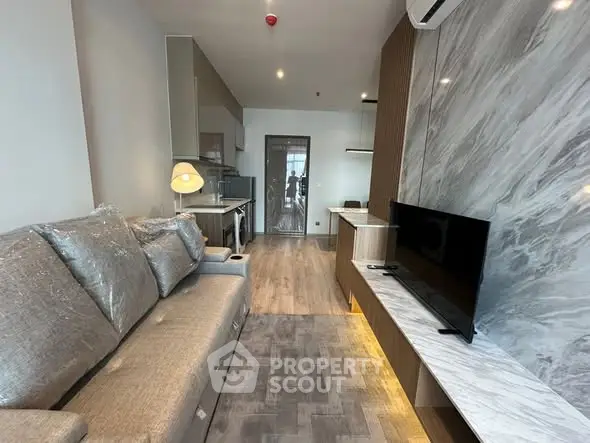 Modern living room with sleek design and marble accents, featuring a comfortable sofa and flat-screen TV.