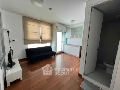 Modern living room with wooden flooring, compact kitchen, and natural light.