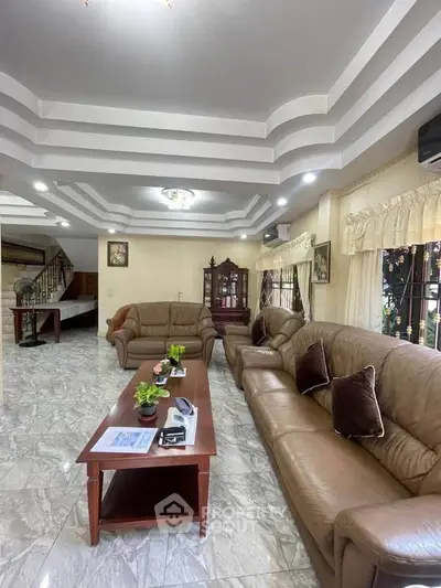Spacious living room with elegant leather sofas and stylish ceiling design.