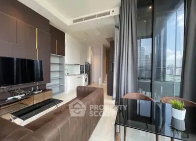 Modern living room with open kitchen and city view balcony, featuring sleek furniture and natural light.