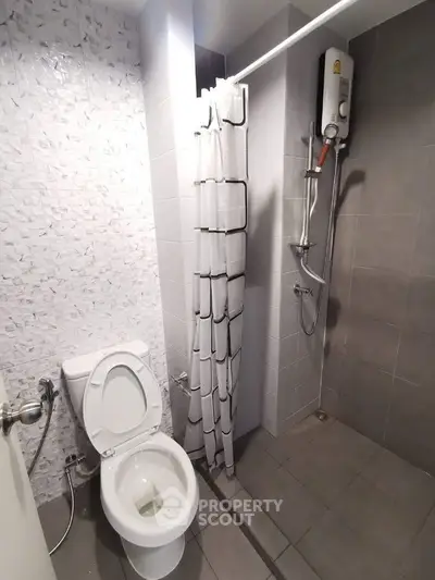 Modern bathroom with shower and toilet in sleek gray tiles.