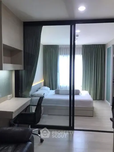 Modern bedroom with glass partition and study area, featuring sleek design and natural light.