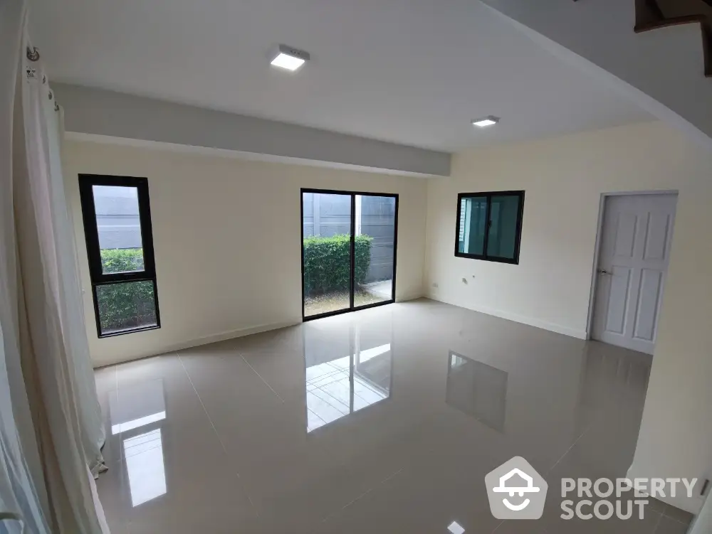 Spacious and bright living room with glossy tiled flooring, large windows offering ample natural light, and a neutral color palette ready for personalization.