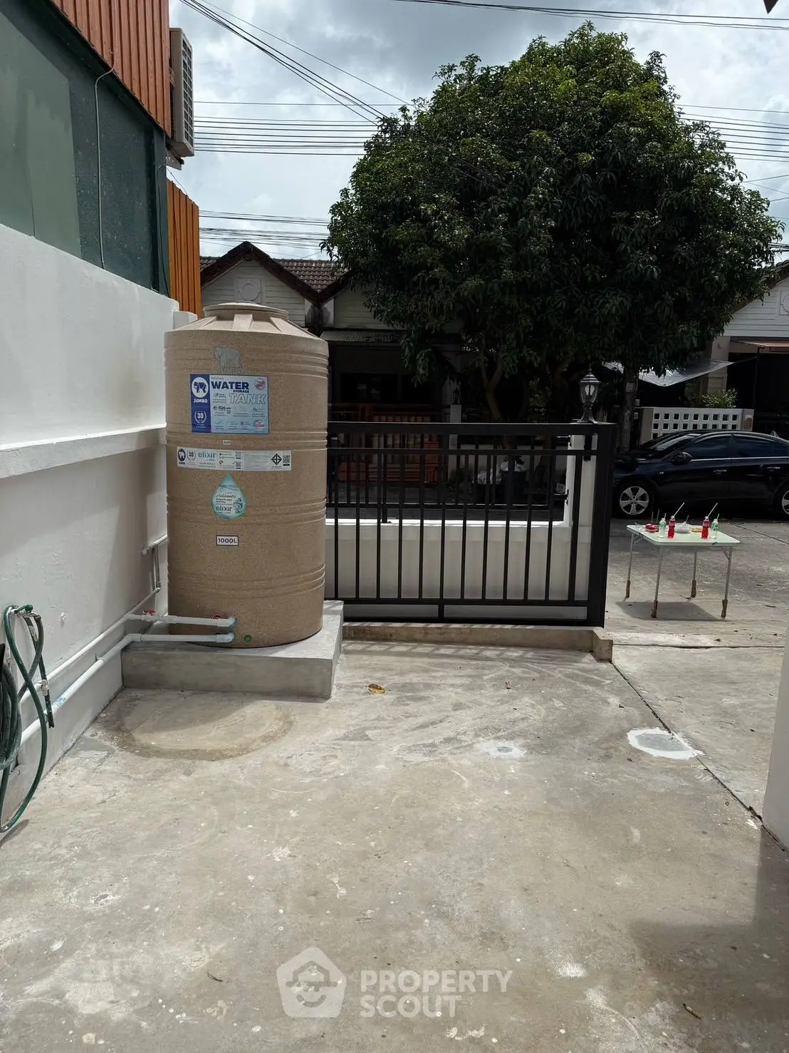 Spacious outdoor area with water tank and secure fencing in a residential setting.