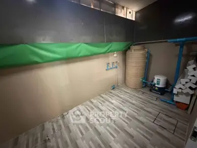 Spacious utility room with water tank and tiled flooring, ideal for storage or laundry setup.