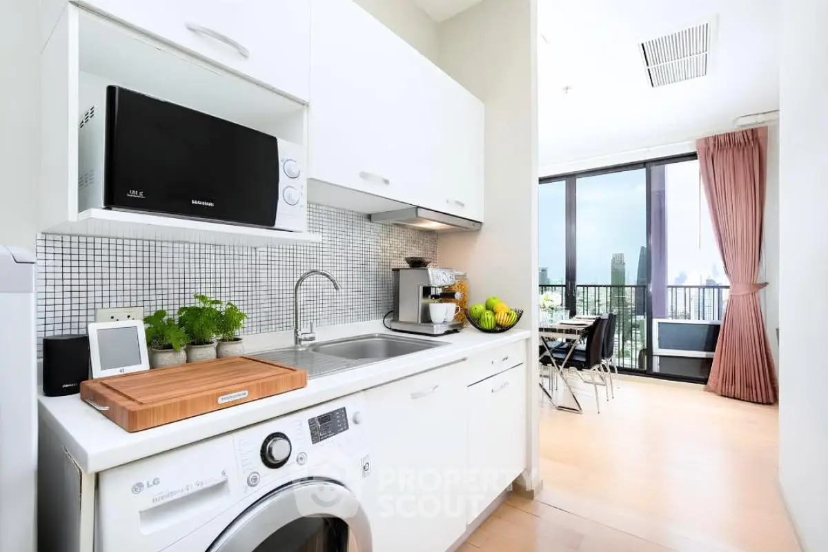 Modern kitchen with sleek appliances and open layout leading to a balcony with city view.