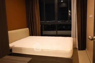 Cozy bedroom with city view, featuring a comfortable bed and large window for natural light.