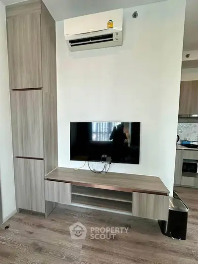 Modern living room with wall-mounted TV and air conditioning in stylish apartment.