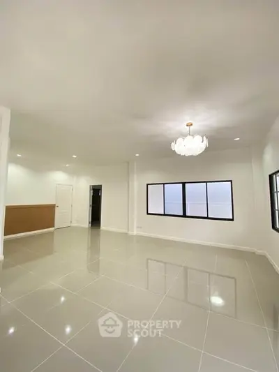 Spacious modern living room with elegant chandelier and large windows.