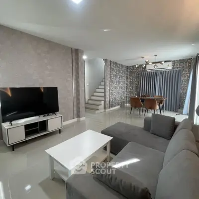 Modern living room with sleek furniture and stylish decor, featuring a spacious layout and elegant staircase.