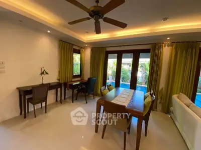 Spacious living room with pool view, elegant furniture, and ceiling fan in a modern home.