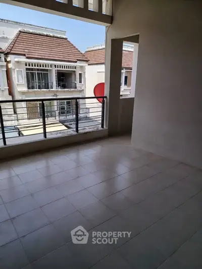 Spacious balcony with tiled flooring and view of neighboring buildings, perfect for relaxation.