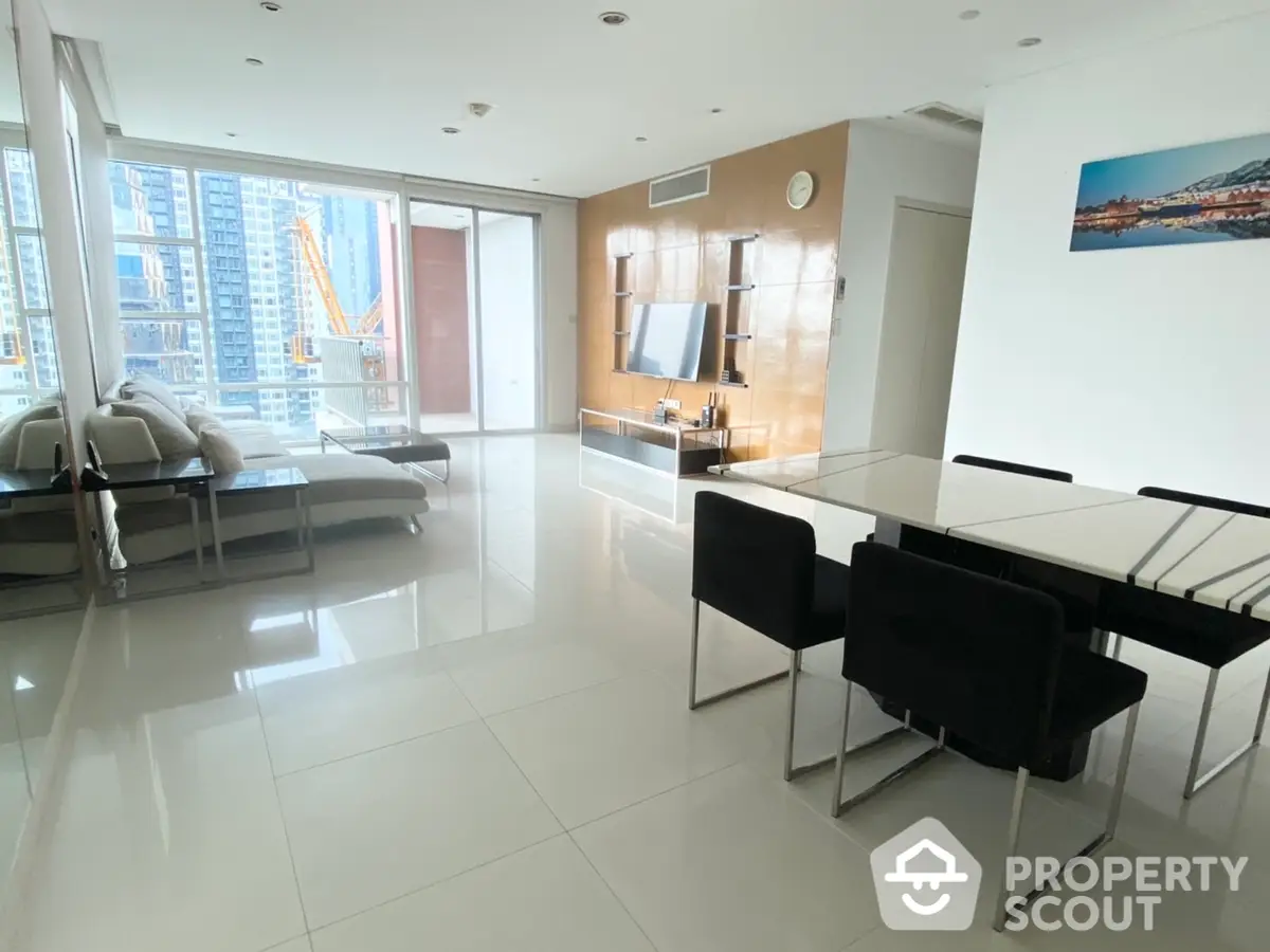 Spacious modern living room with gleaming floor tiles, large windows allowing ample natural light, and a sleek dining area perfect for entertaining.