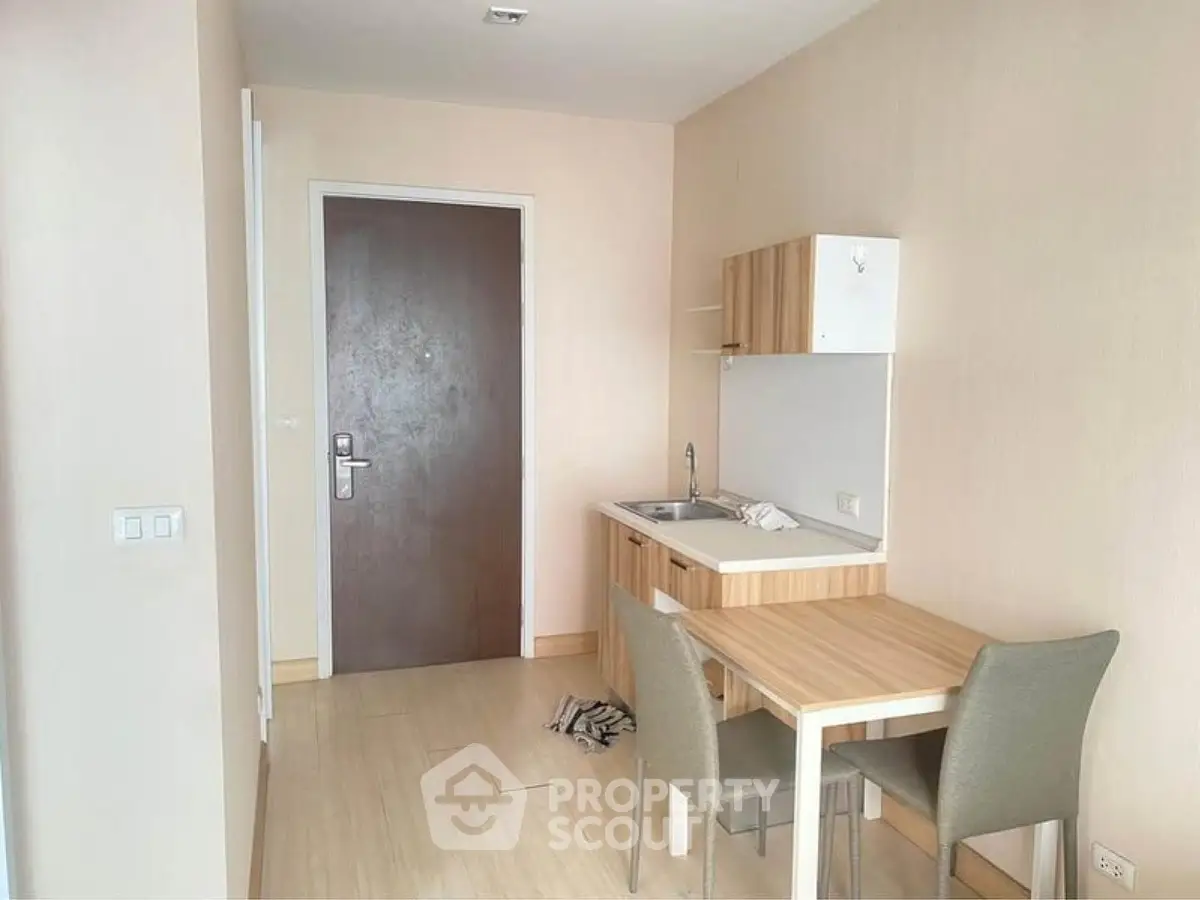 Compact studio apartment with kitchenette and dining area, featuring modern furniture and neutral tones.