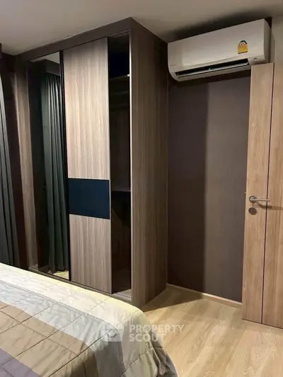 Modern bedroom with sleek wooden wardrobe and air conditioning unit, perfect for comfortable living.