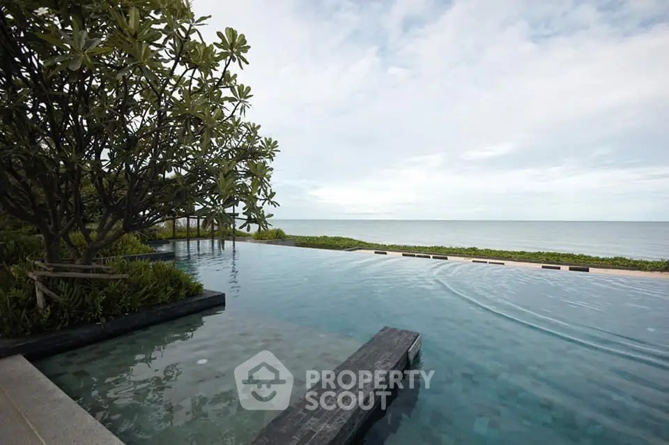 Luxurious beachfront infinity pool with stunning ocean view and lush greenery.