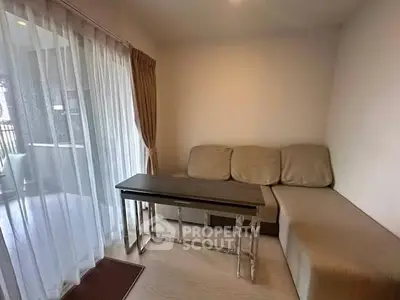 Cozy living room with beige sofa and glass sliding doors leading to a balcony.