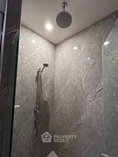 Luxurious marble-tiled shower with modern fixtures in a high-end bathroom.