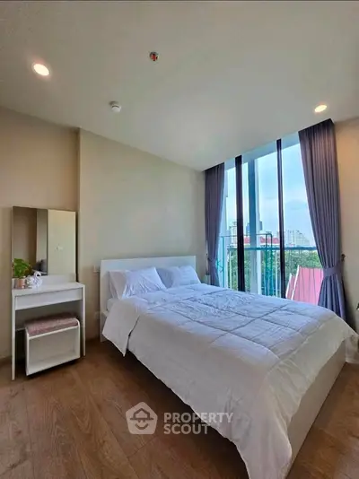 Modern bedroom with large windows and city view, featuring a cozy bed and stylish decor.