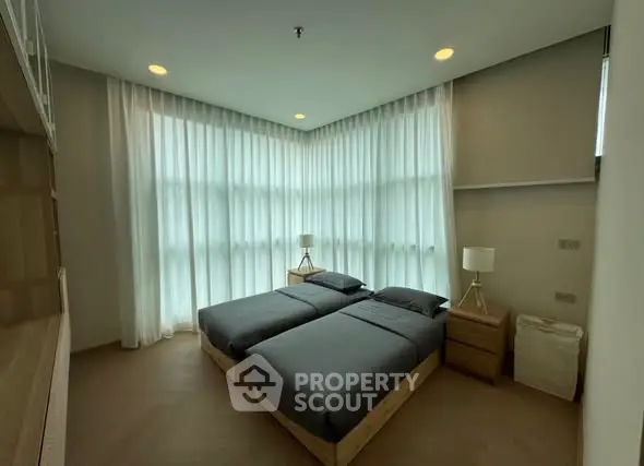 Modern bedroom with twin beds and large windows in a stylish apartment.