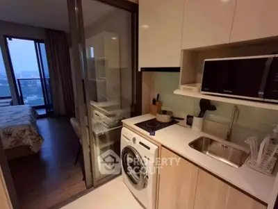 Modern compact kitchen with washing machine and microwave in stylish apartment