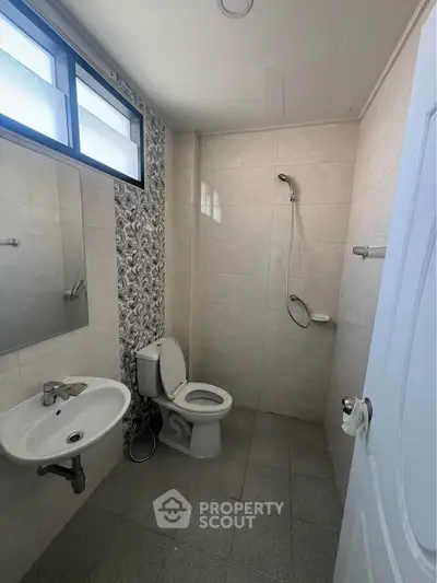 Modern bathroom with tiled walls, shower, and window for natural light.