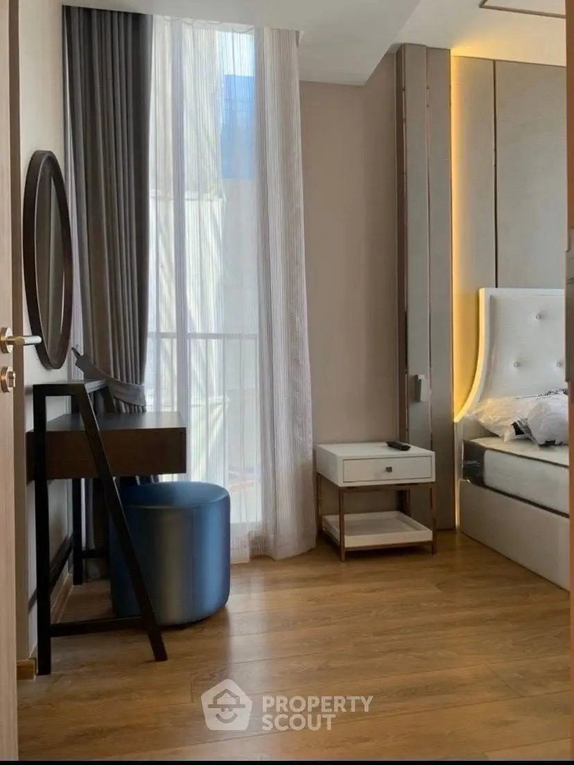 Elegant bedroom with modern decor and natural light, featuring a stylish vanity and plush bedding.
