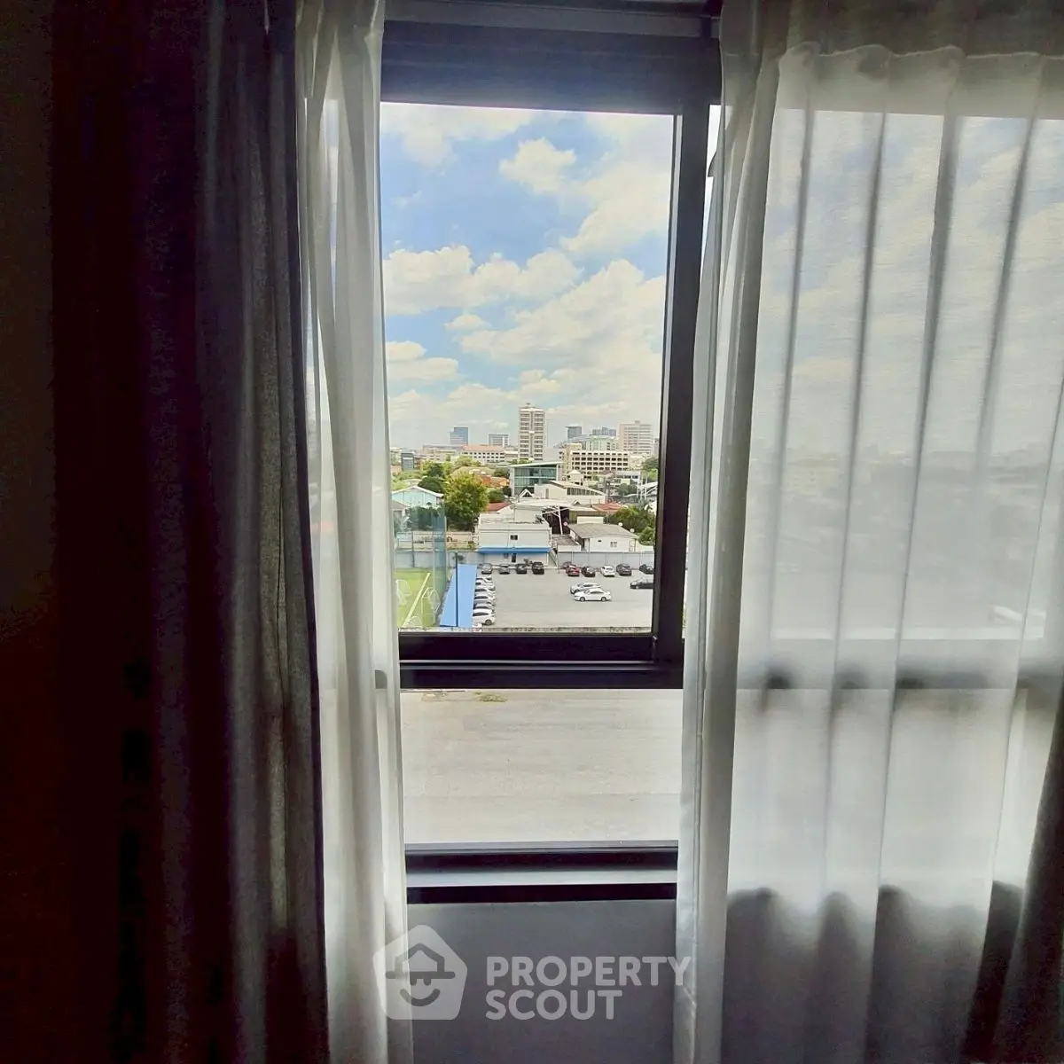 Stunning cityscape view through a window with sheer curtains, perfect for urban living.