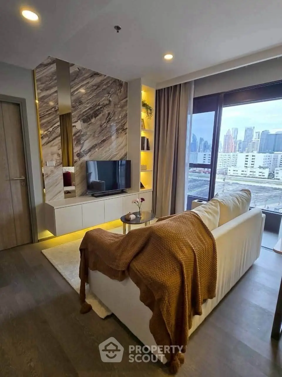 Modern living room with city view, featuring stylish decor and cozy ambiance.