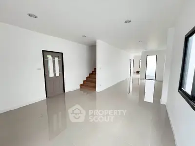 Spacious modern interior with sleek tile flooring and staircase, ideal for customization.