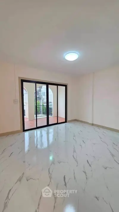 Spacious living room with marble flooring and large sliding glass doors leading to a balcony.