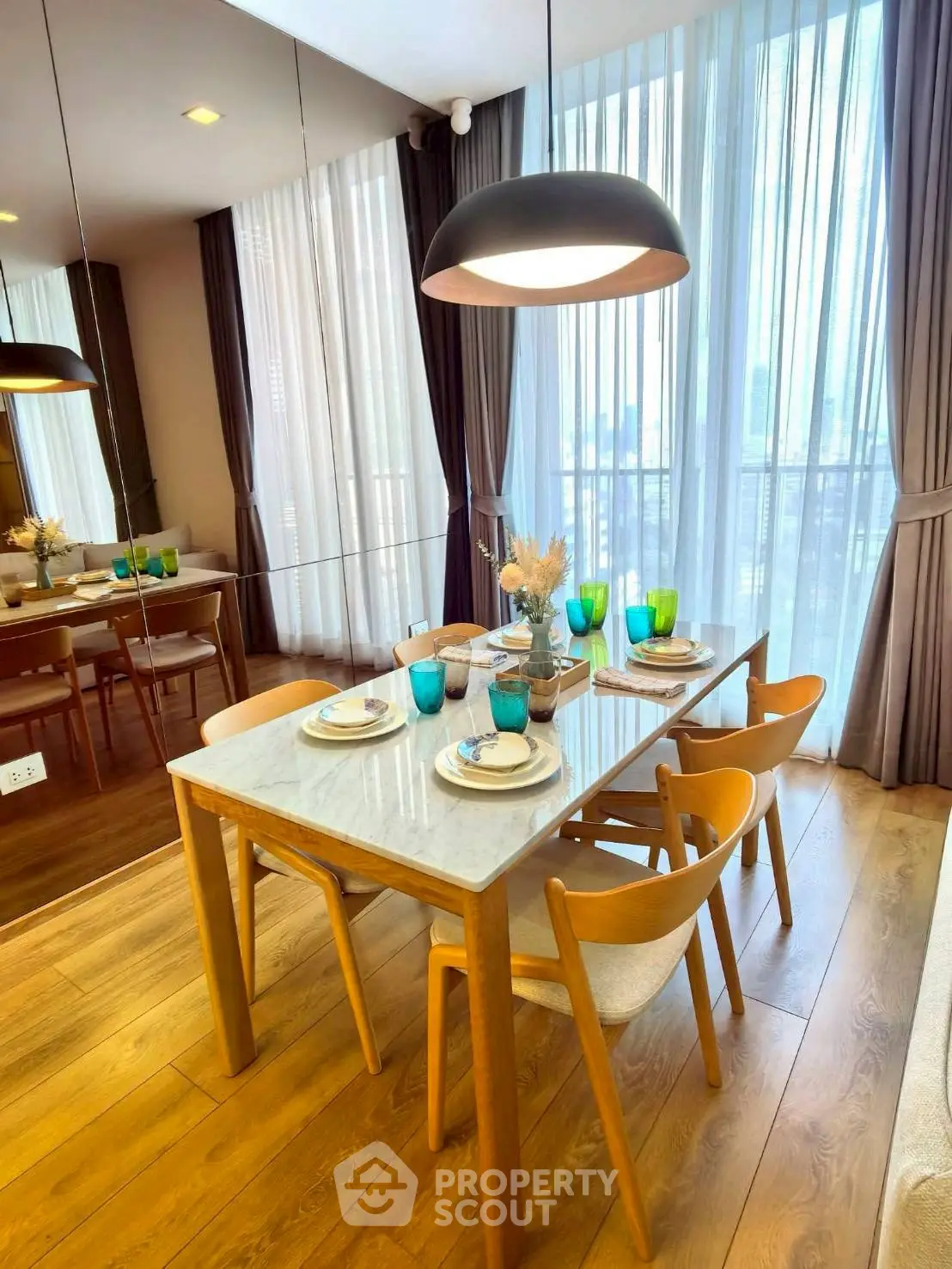 Elegant dining area with wooden table and chairs, large windows, and stylish decor.