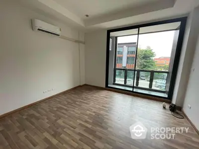 Spacious empty room with large window and wood flooring in modern apartment