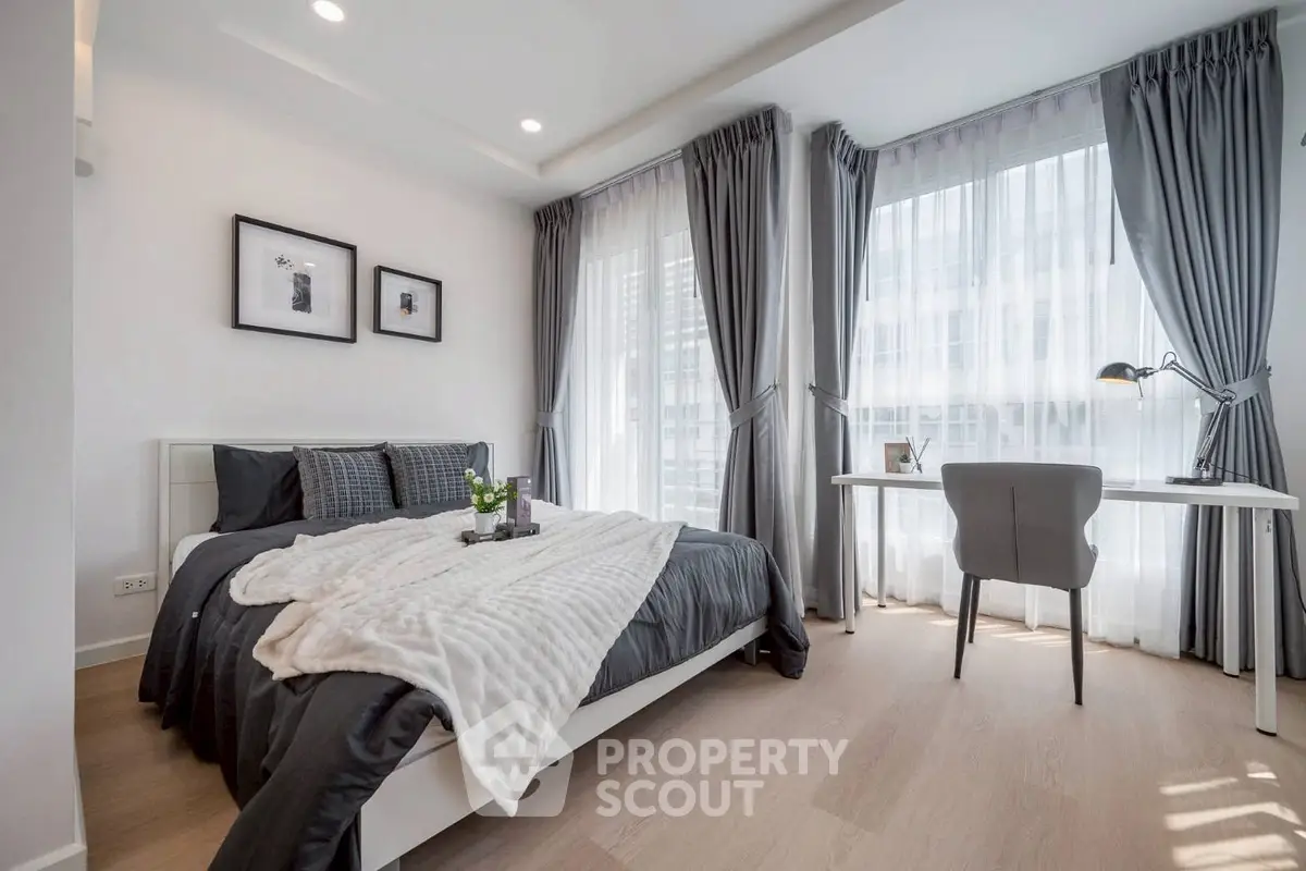 Modern bedroom with stylish decor and natural light, featuring a cozy bed and a sleek work desk.