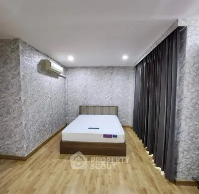 Spacious bedroom with modern design and elegant flooring, featuring a comfortable bed and stylish curtains.