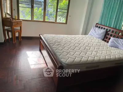 Spacious bedroom with wooden flooring and large windows for natural light