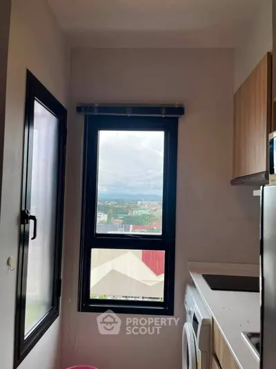 Compact kitchen with washing machine and scenic window view in modern apartment.