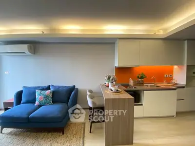 Modern open-layout living room with stylish kitchen and cozy blue sofa