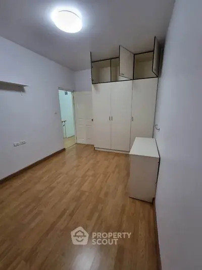 Spacious bedroom with wooden flooring and ample storage space.