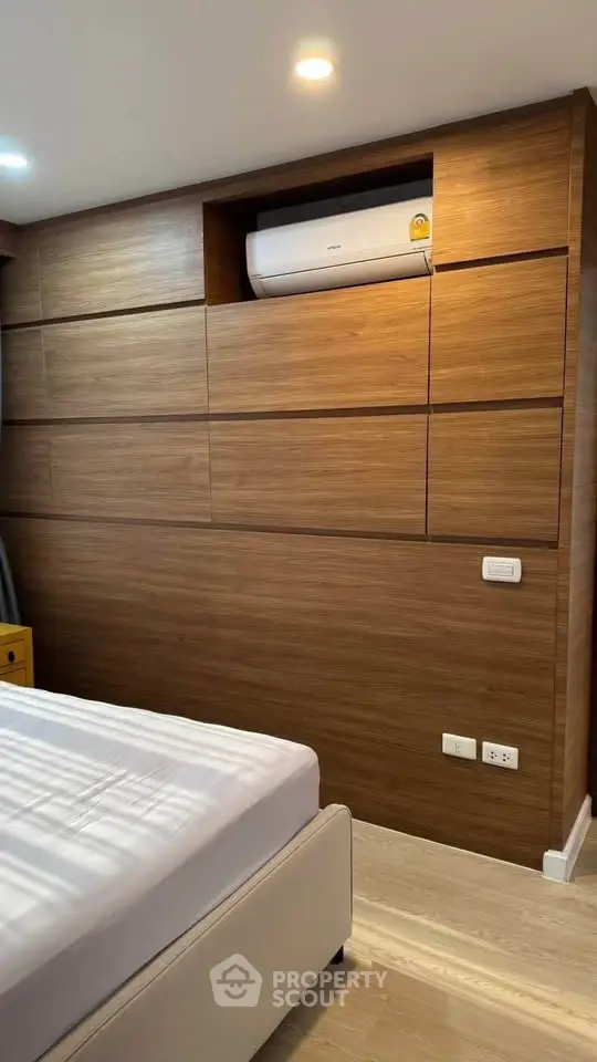 Modern bedroom with wooden paneling and built-in air conditioning unit, offering a sleek and cozy ambiance.