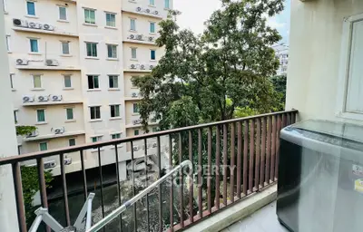 Charming balcony view overlooking lush greenery and modern building facade, perfect for urban living.