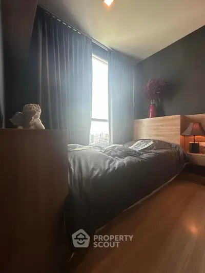 Cozy bedroom with modern decor and large window offering natural light.